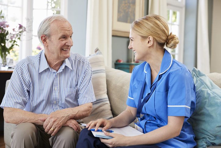 A nurse talking with an older man at home